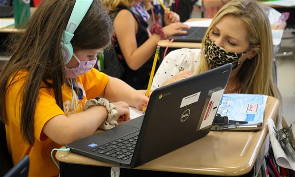 teacher works with student on laptop